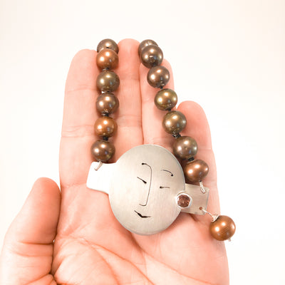 Sunstone Necklace with Bronze Pearls and Unmentionables Clasp by Ling-Yen Jones held in hand