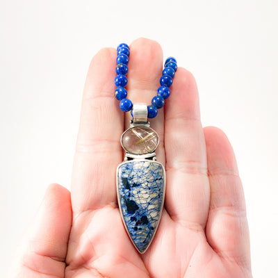 Sterling Siberian Azurite Pendant on Lapis Beads by Susan Schulz held in hand