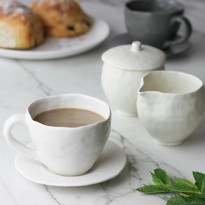 White Latte Cup and Saucer with coffee and croissants on marble counter by Nona Kelhofer